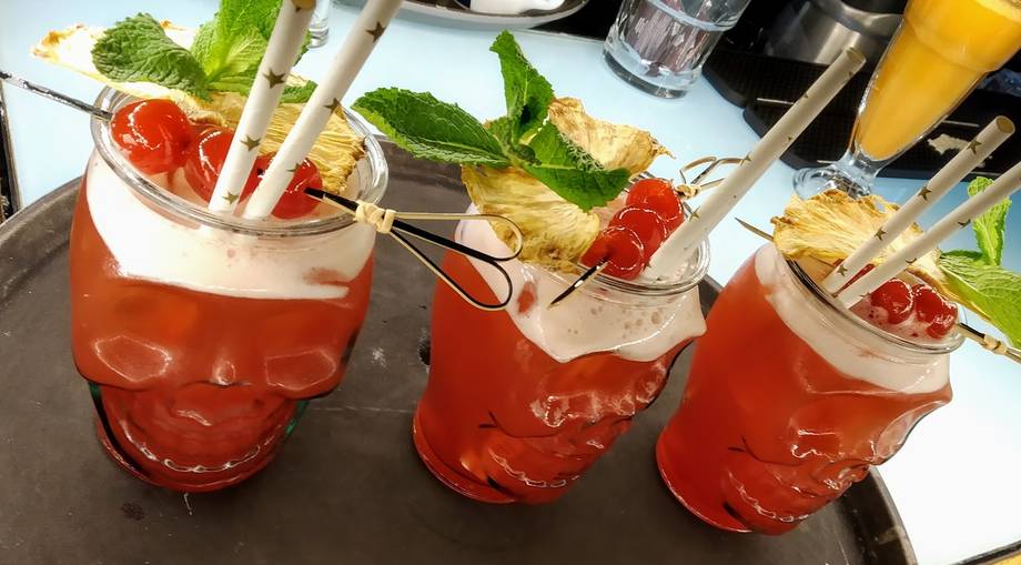 Three ruby-red cocktails with fresh mint garnish and ice