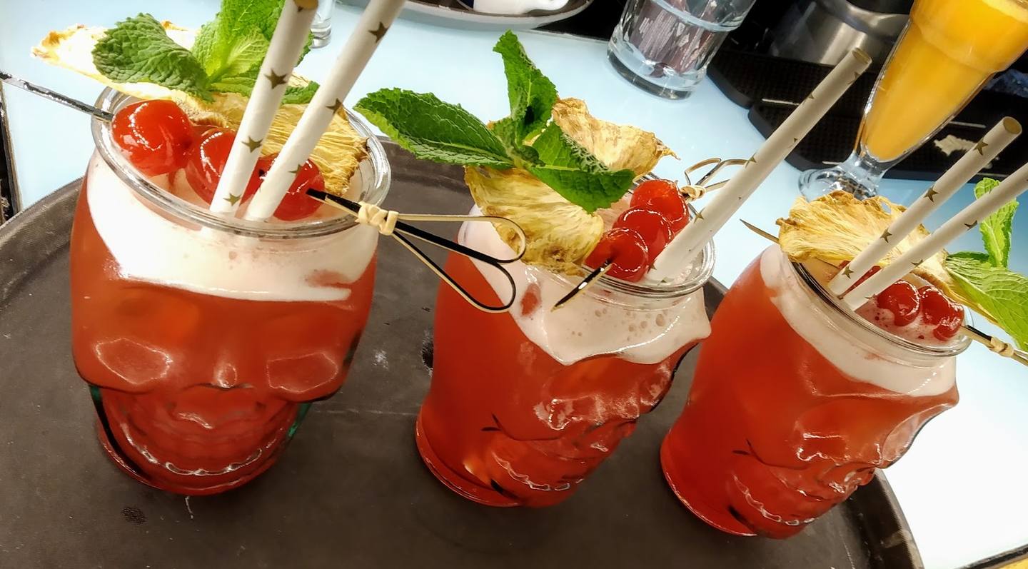 Three ruby-red cocktails with fresh mint garnish and ice