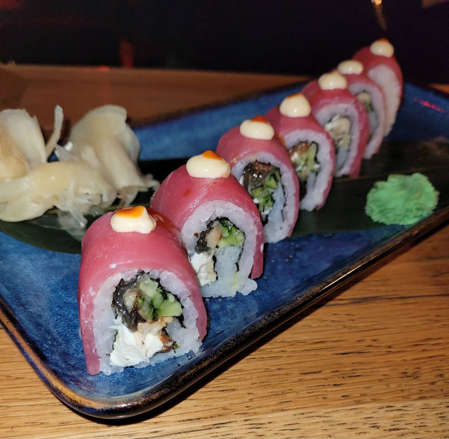 Plated sushi rolls with salmon and wasabi on blue ceramic dish