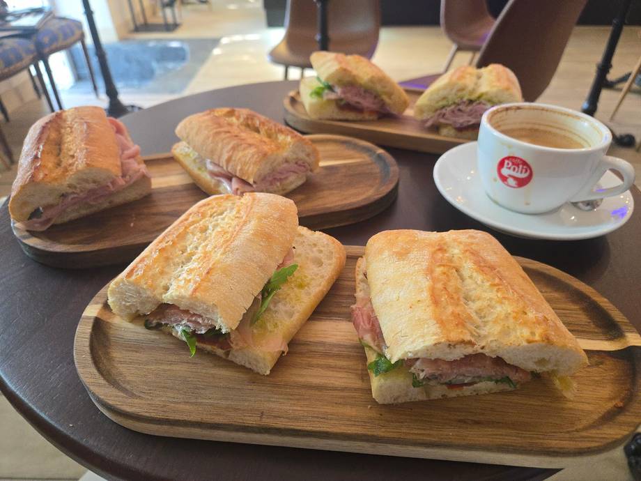 Assorted sandwiches and pastries with coffee service on wooden boards