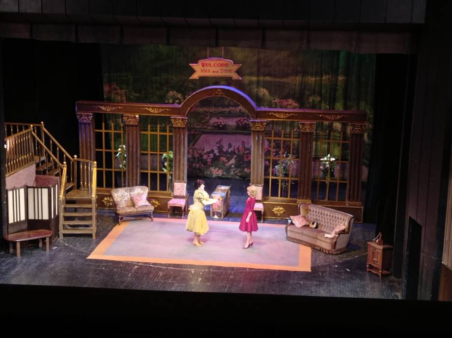 Theater stage set with period architectural backdrop and performers in costume