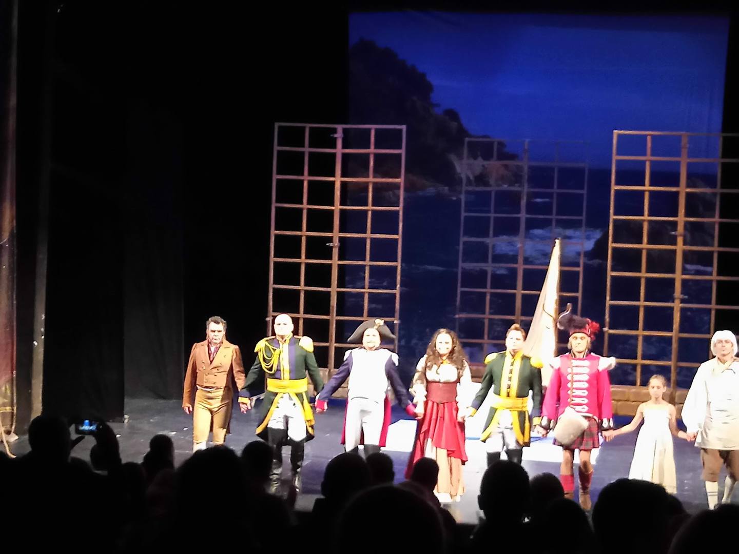 Theater performance with cast taking curtain call on lit stage