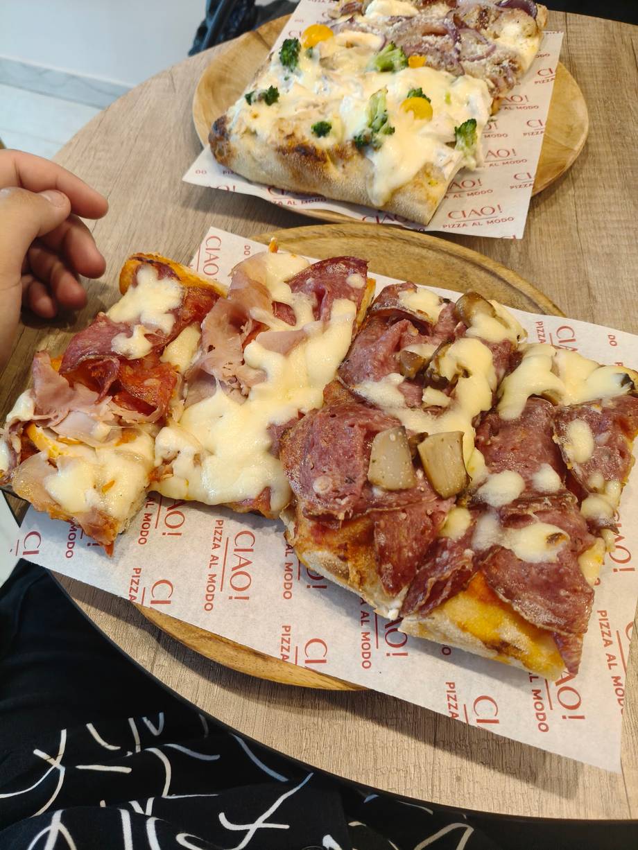 Sliced pizza with ham and cheese on branded wooden board