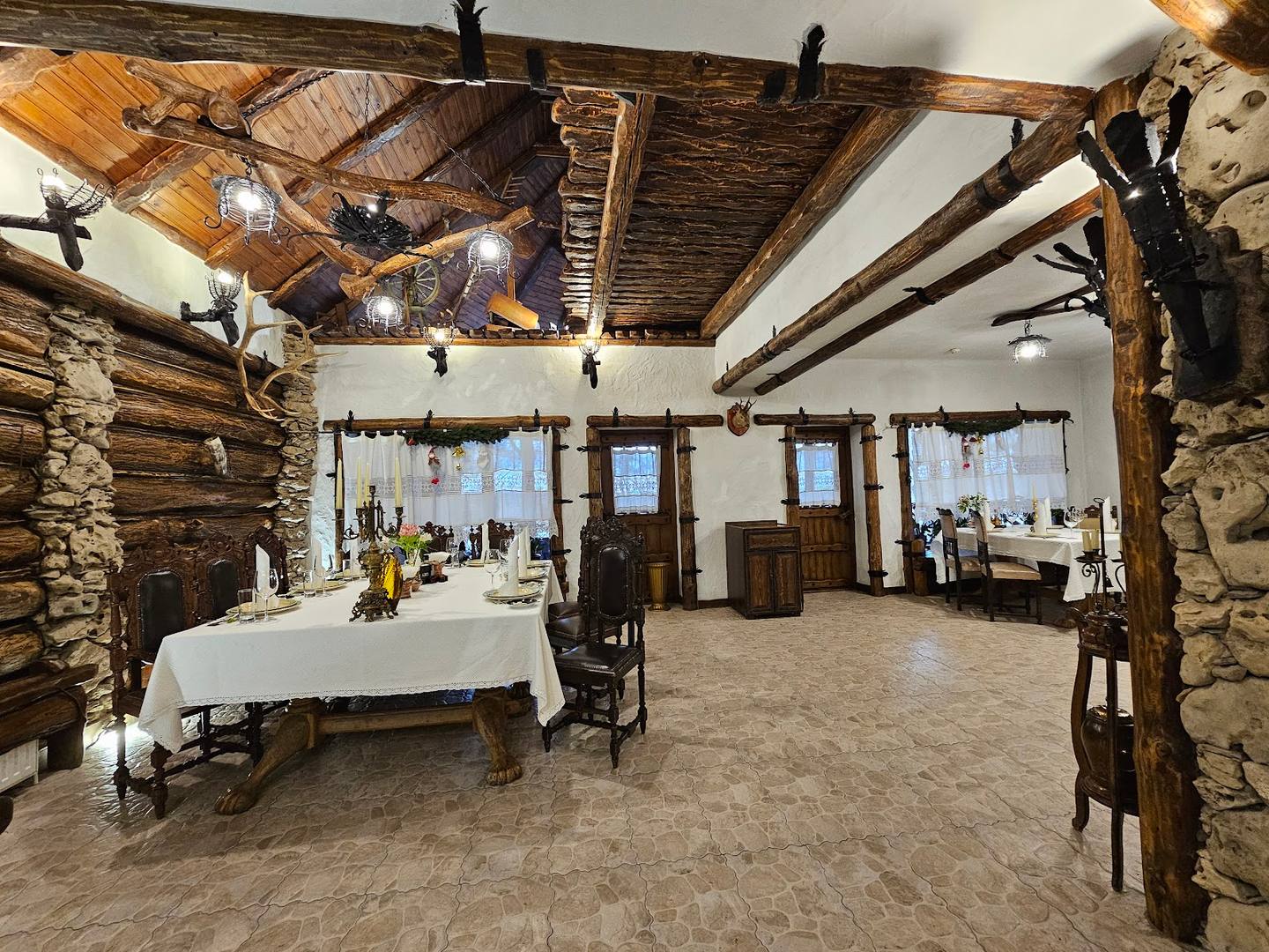 Spacious interior with rustic wooden beams, stone walls, and natural lighting from large windows