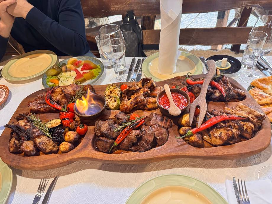 Mixed grilled meat and seafood platter on wooden board with table setting