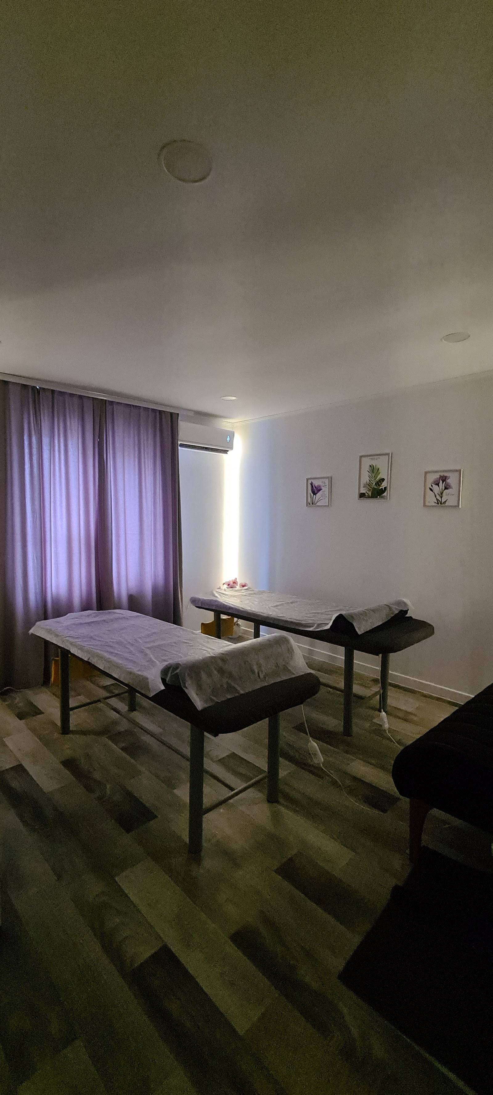 Spa treatment room with two massage beds and purple curtains