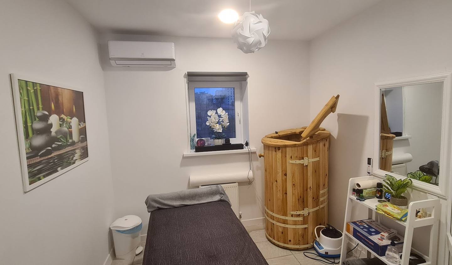 Sauna treatment room interior with wooden barrel, bench seating, and wellness products