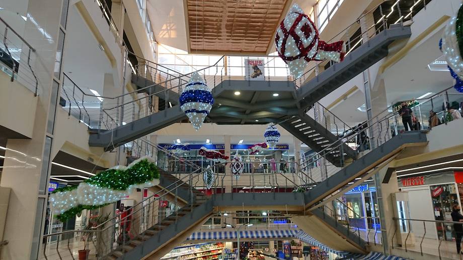 Multi-level shopping mall interior with escalators and storefronts