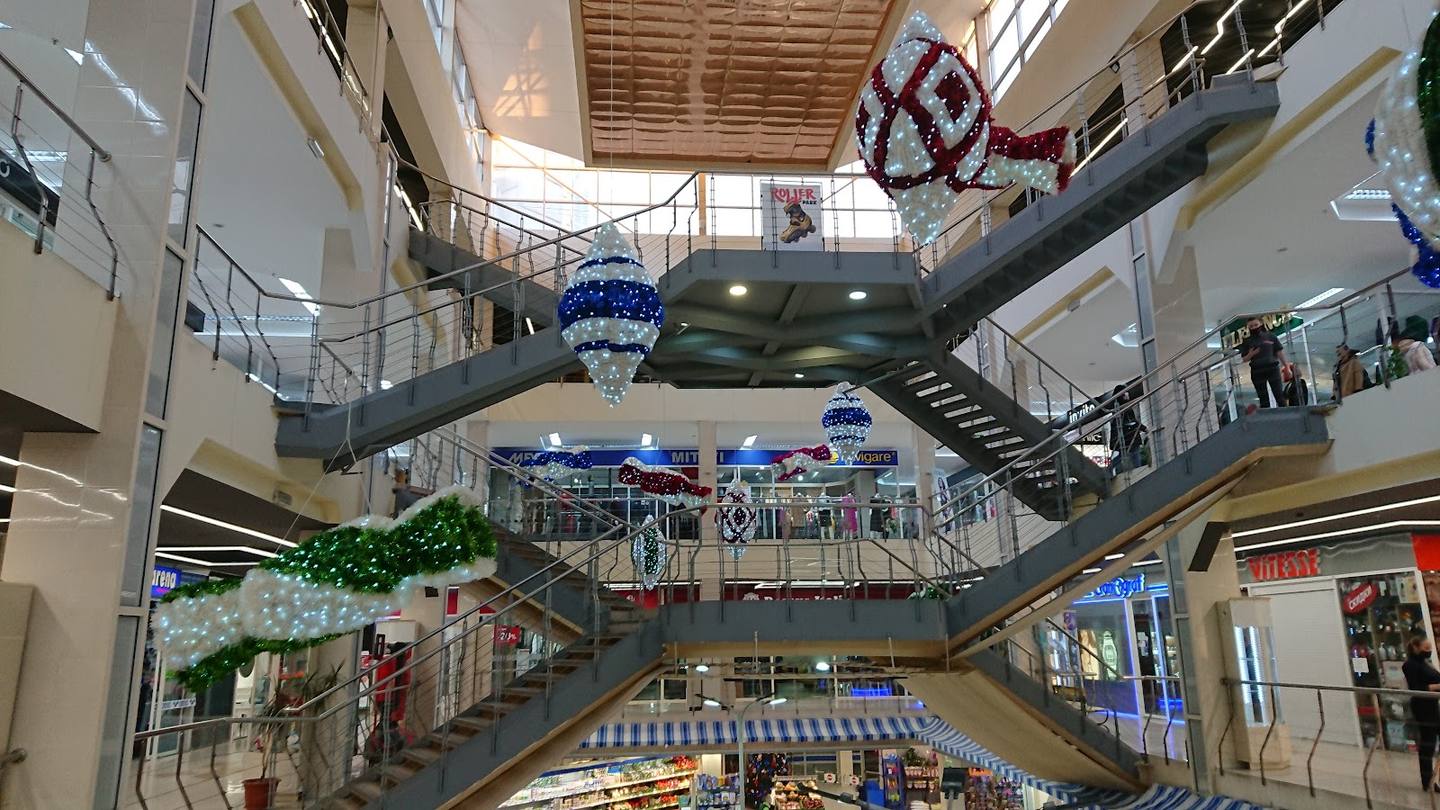 Multi-level shopping mall interior with escalators and storefronts
