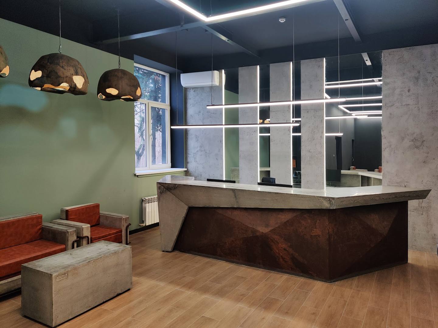 Modern spa reception area with curved dark wood desk, ambient pendant lighting, and contemporary furnishings