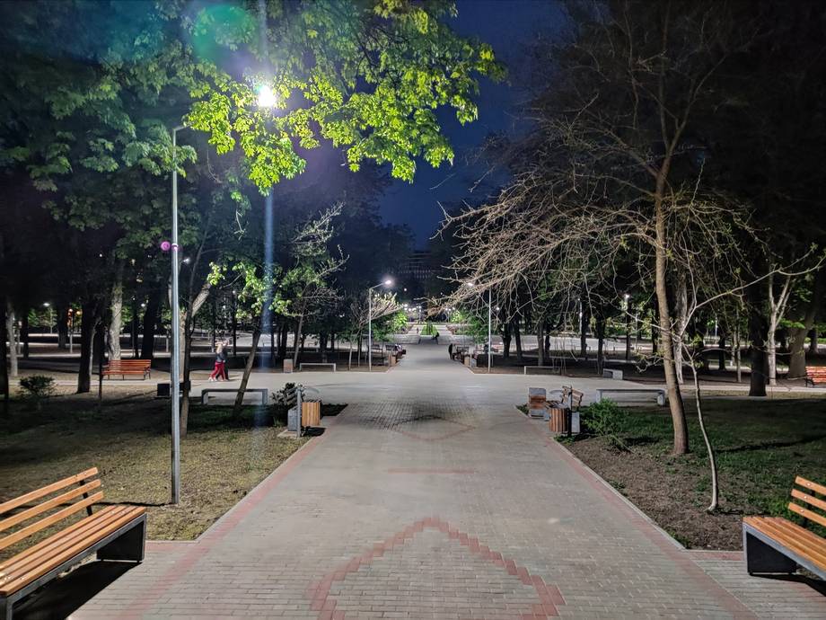 Evening lighting of landscaped park pathway with trees and benches