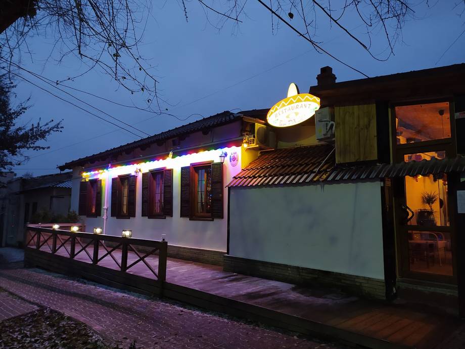 Modern converted railway carriage bar/restaurant with illuminated signage at dusk