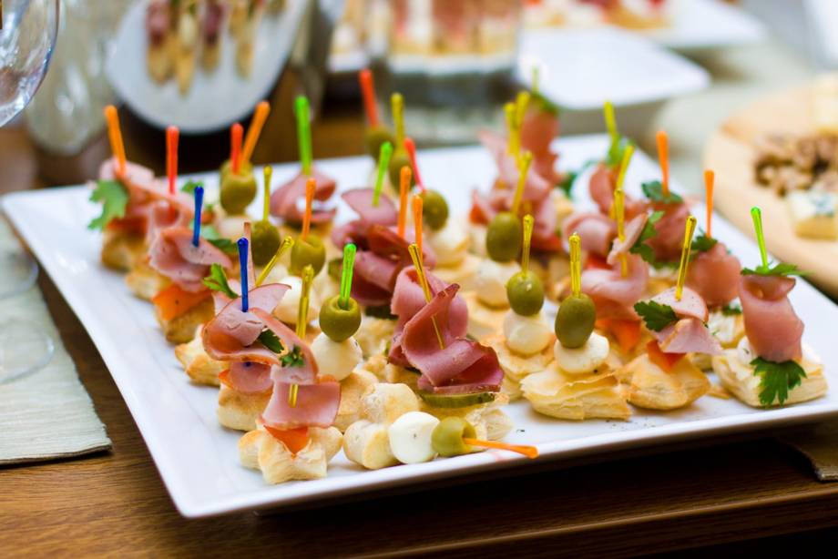 Gourmet appetizers with prosciutto and olives on white platter