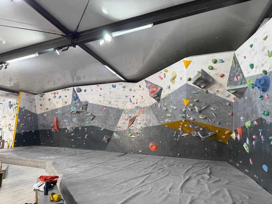 Indoor rock climbing wall with colorful holds and padded flooring