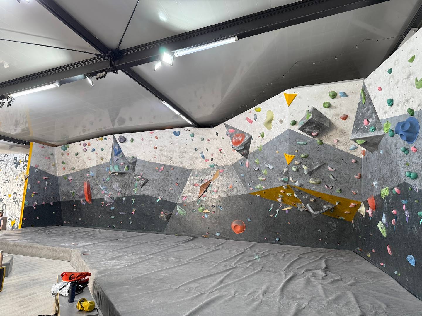 Indoor rock climbing wall with colorful holds and padded flooring