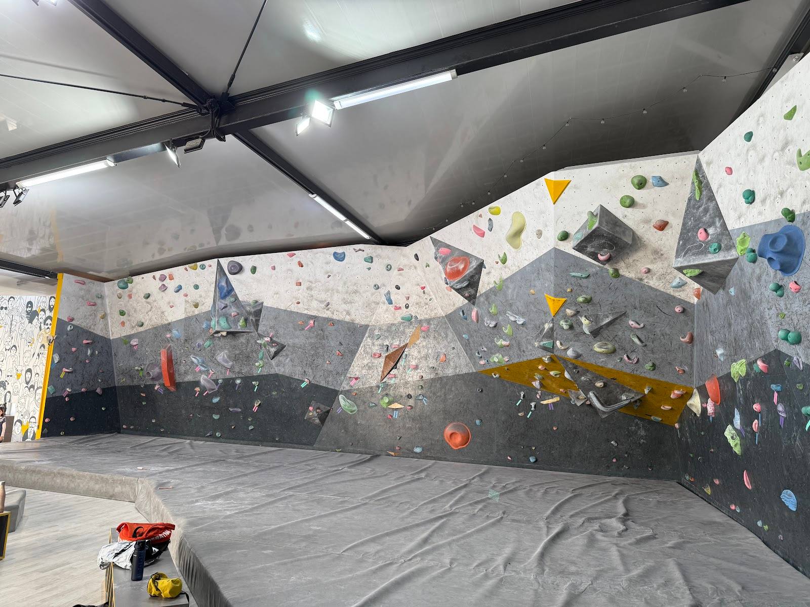 Indoor rock climbing wall with colorful holds and padded flooring