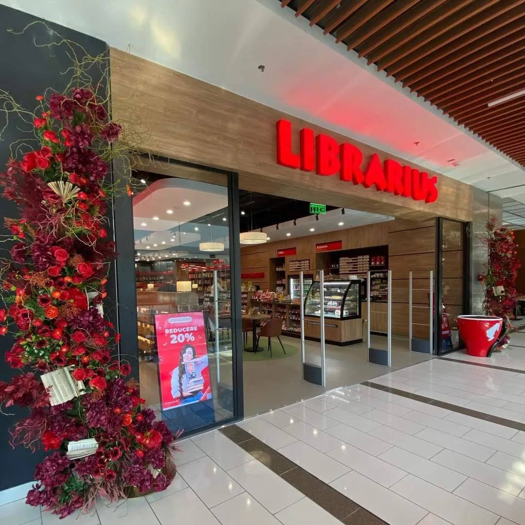 Storefront with red signage and festive floral entrance decoration in shopping mall
