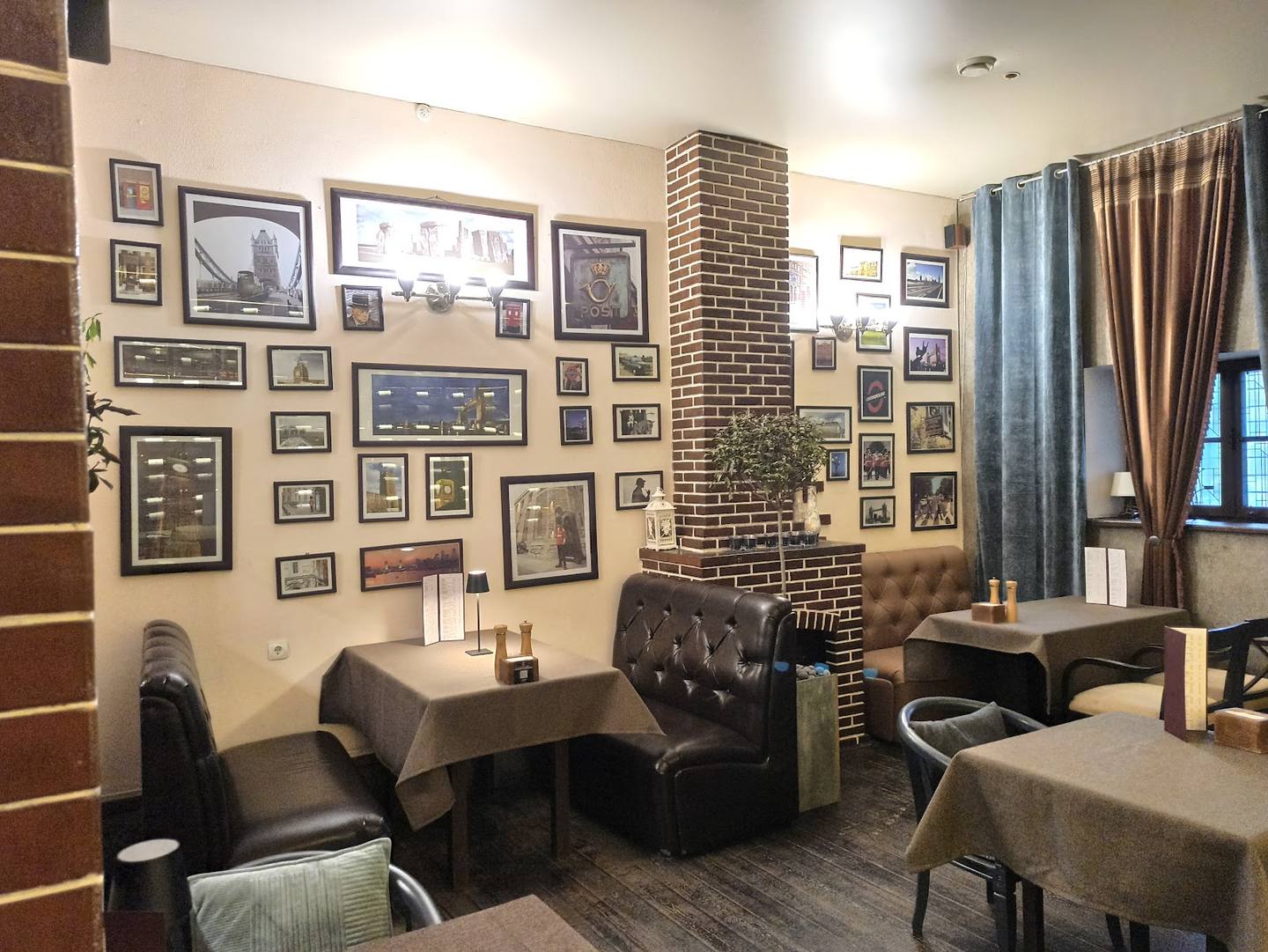 Cozy restaurant interior with exposed brick fireplace, gallery wall, and upholstered seating