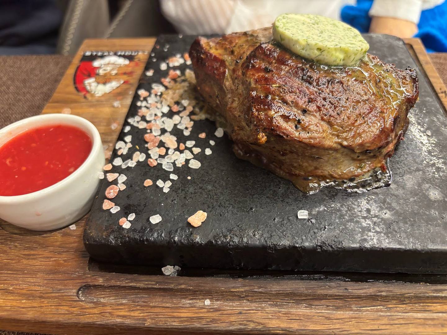 Grilled steak with herb butter, sea salt, and berry sauce on slate board