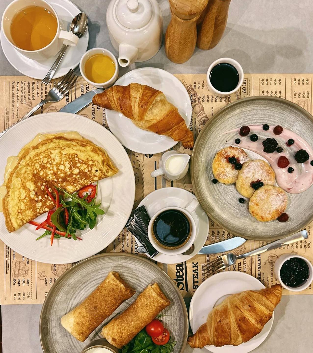 Breakfast spread with croissants, omelet, pancakes, pastries and beverages