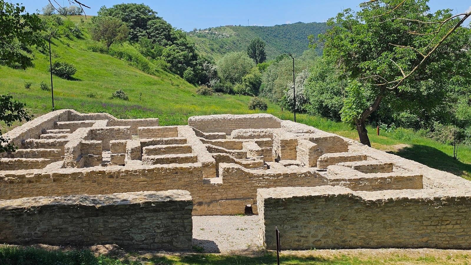 Ancient stone fortress ruins with green hillside landscape backdrop