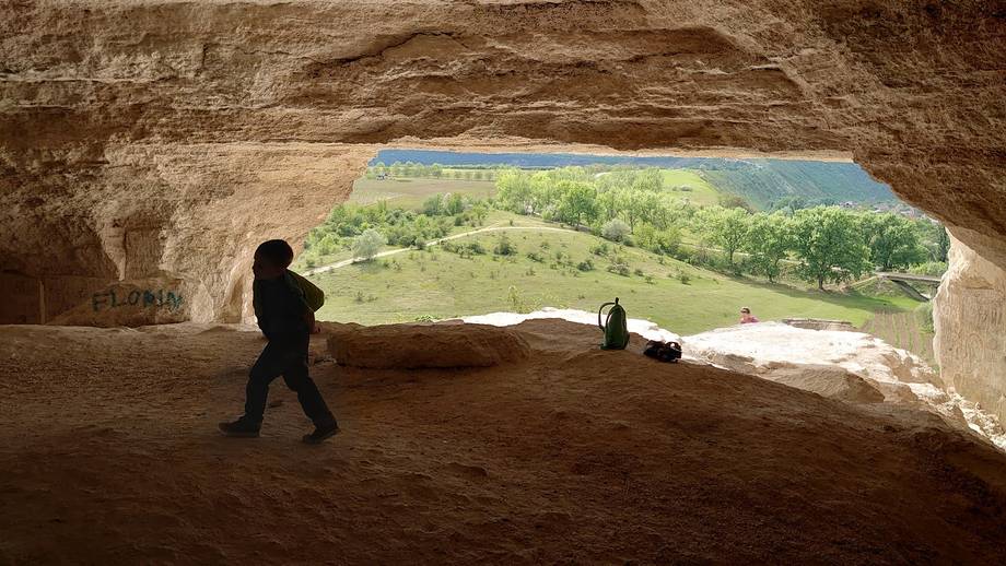 Ancient stone chamber with archway overlooking green valley landscape