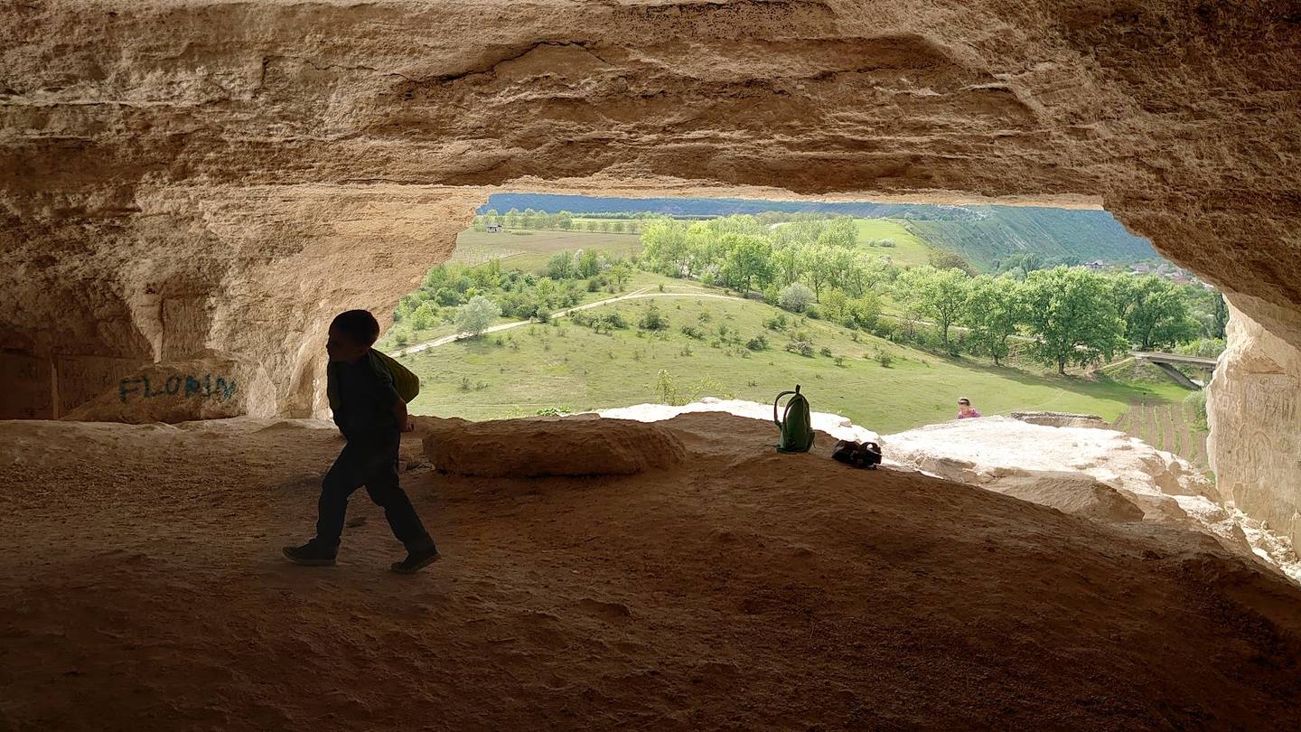 Ancient stone chamber with archway overlooking green valley landscape