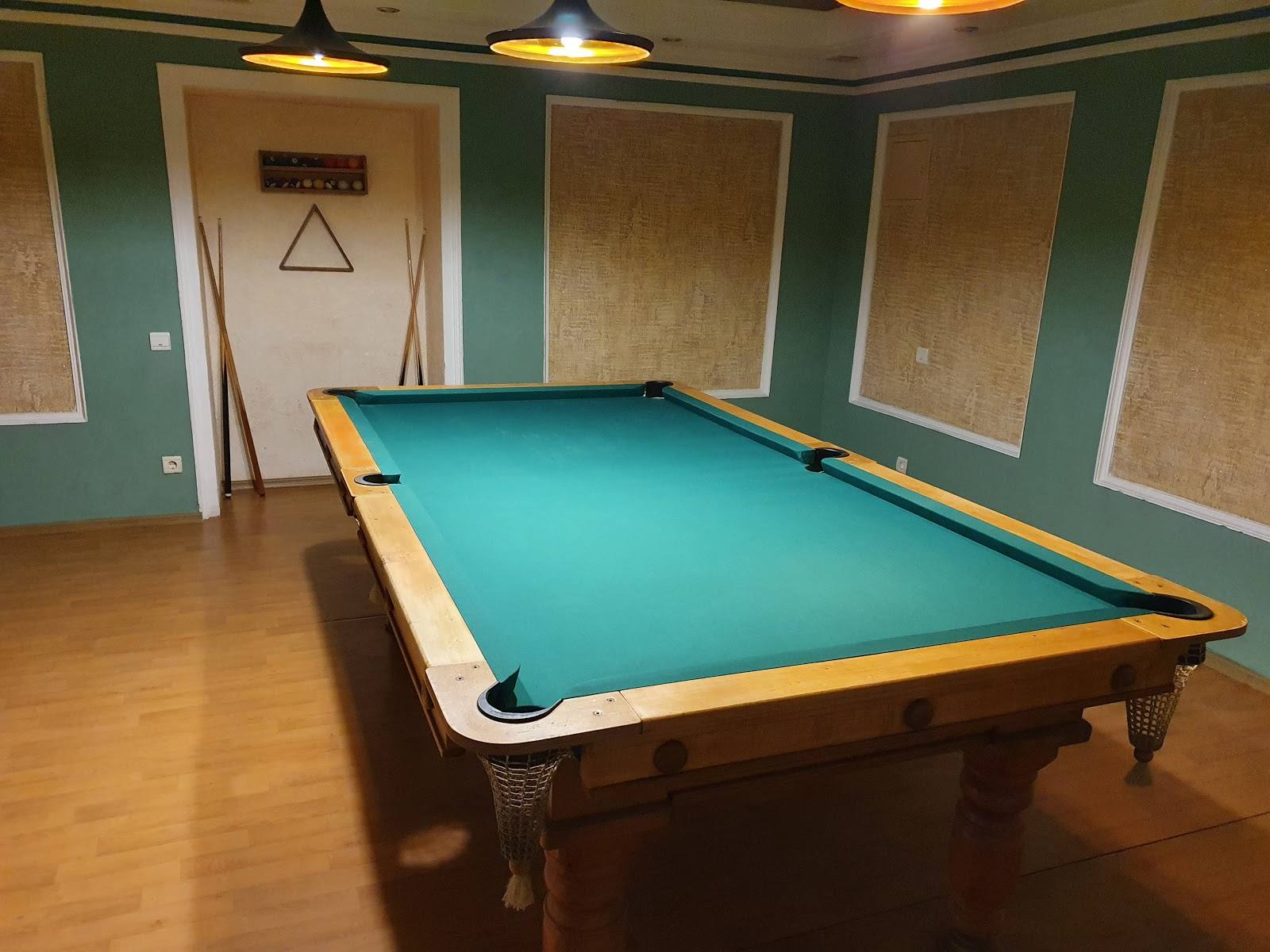 Billiards room with turquoise pool table and teal wall paneling