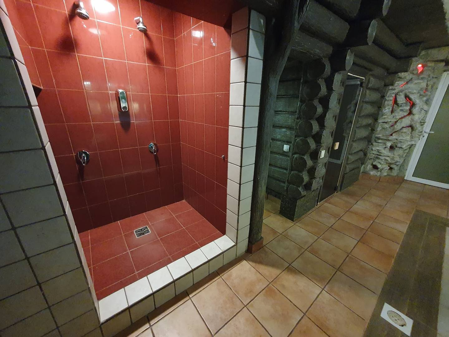 Bathroom shower stall with red tile and bathroom fixtures
