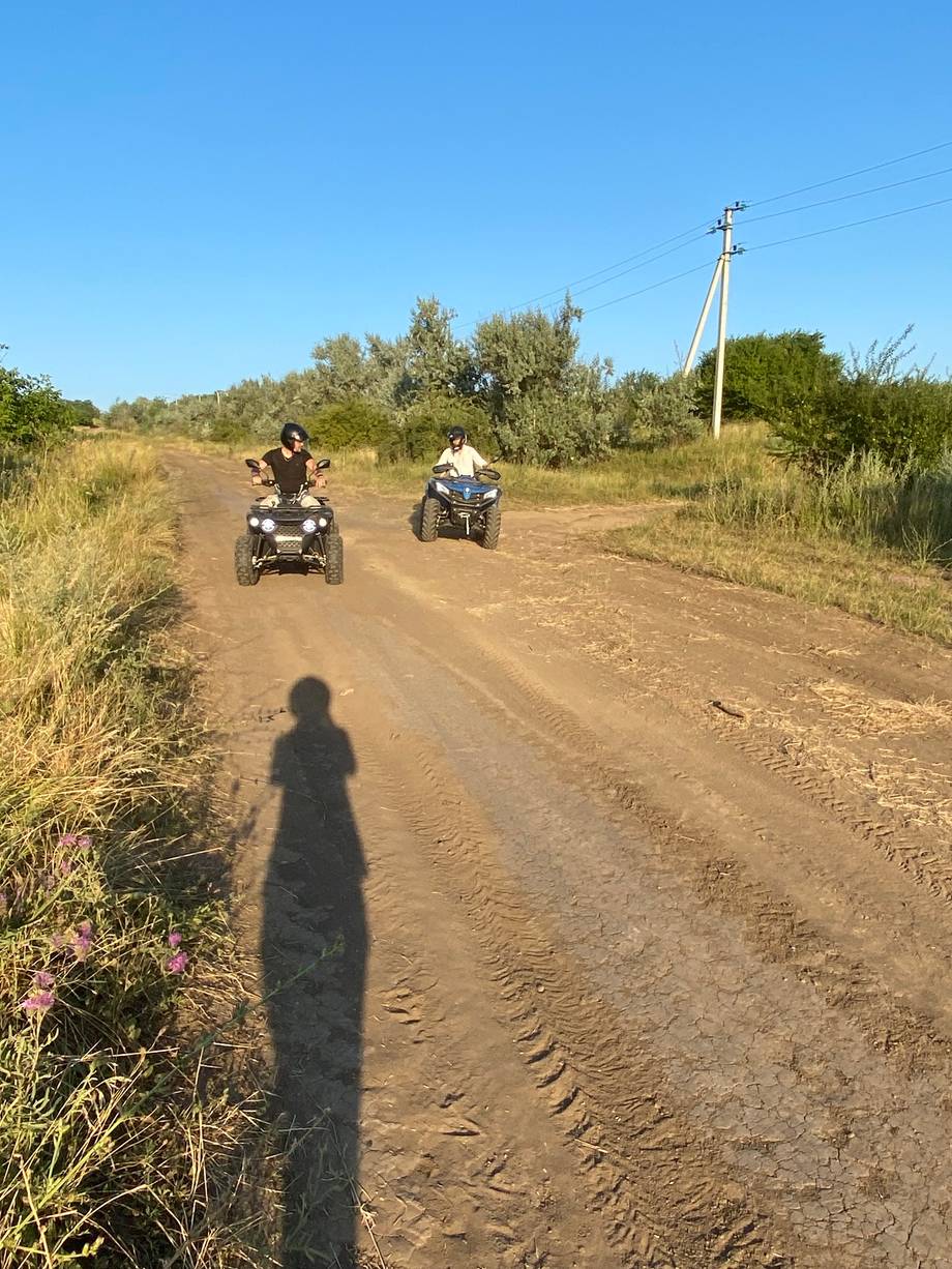 ATV riders on dusty countryside trail under clear sky