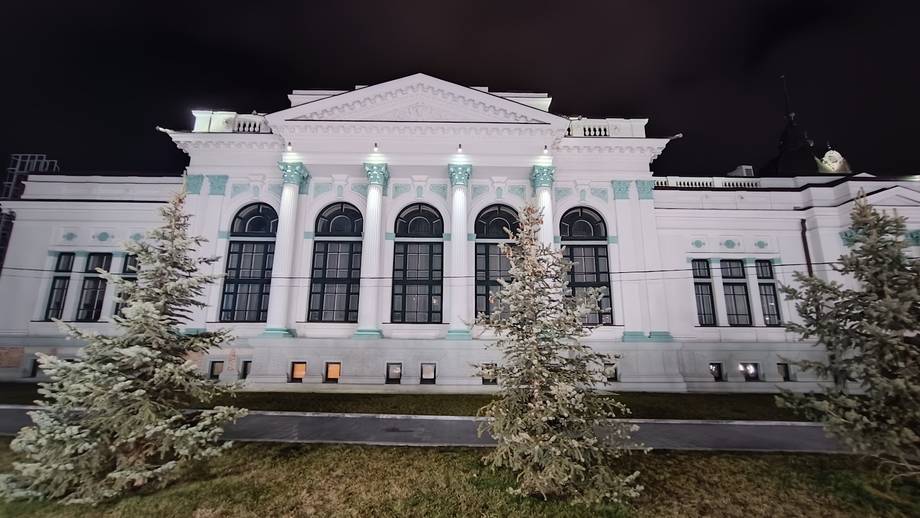 Neoclassical white building exterior with iconic pediment and columned facade at night