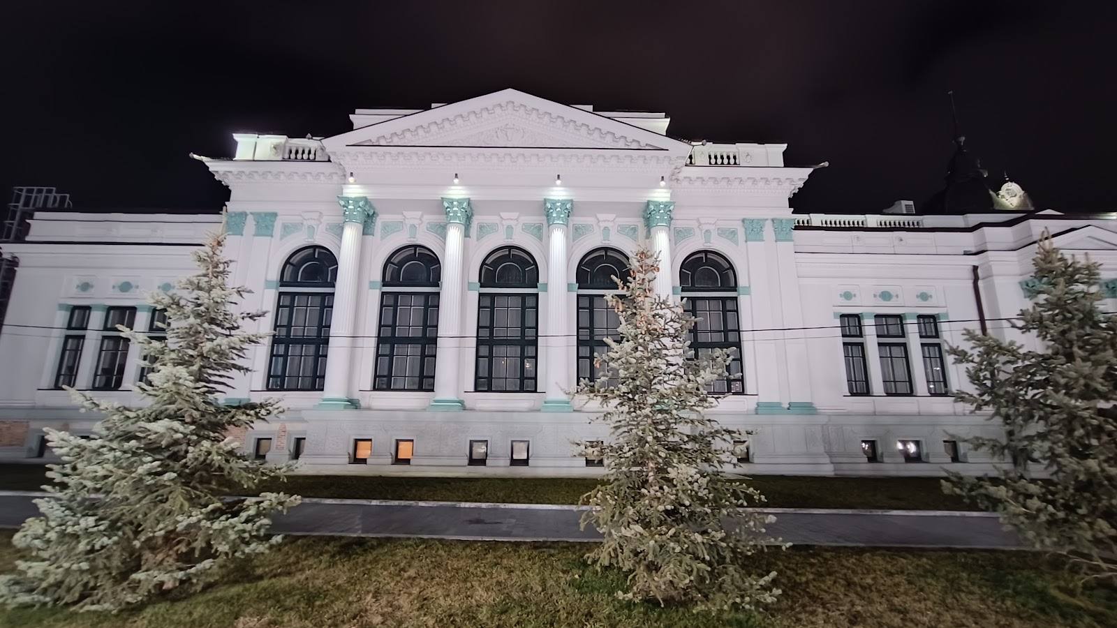Neoclassical white building exterior with iconic pediment and columned facade at night