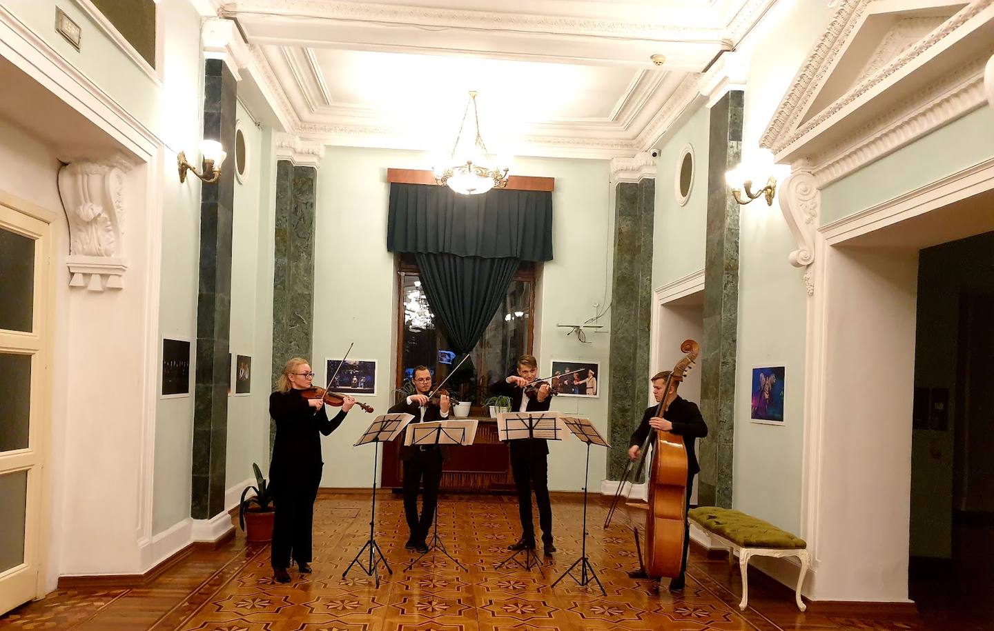 Classical music trio performs in an elegant concert hall with coffered ceiling and ornate green marble columns