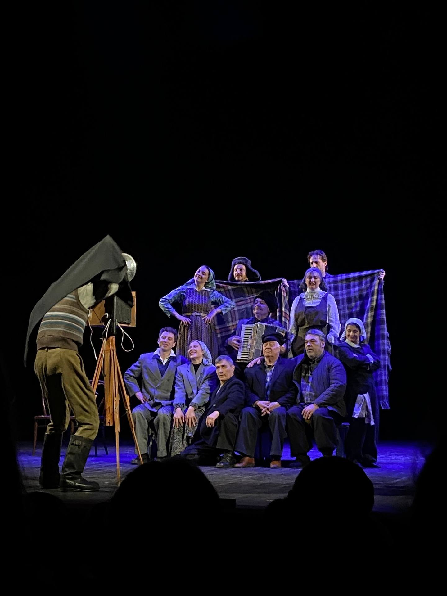 Theater performance with ensemble cast on stage under blue theatrical lighting