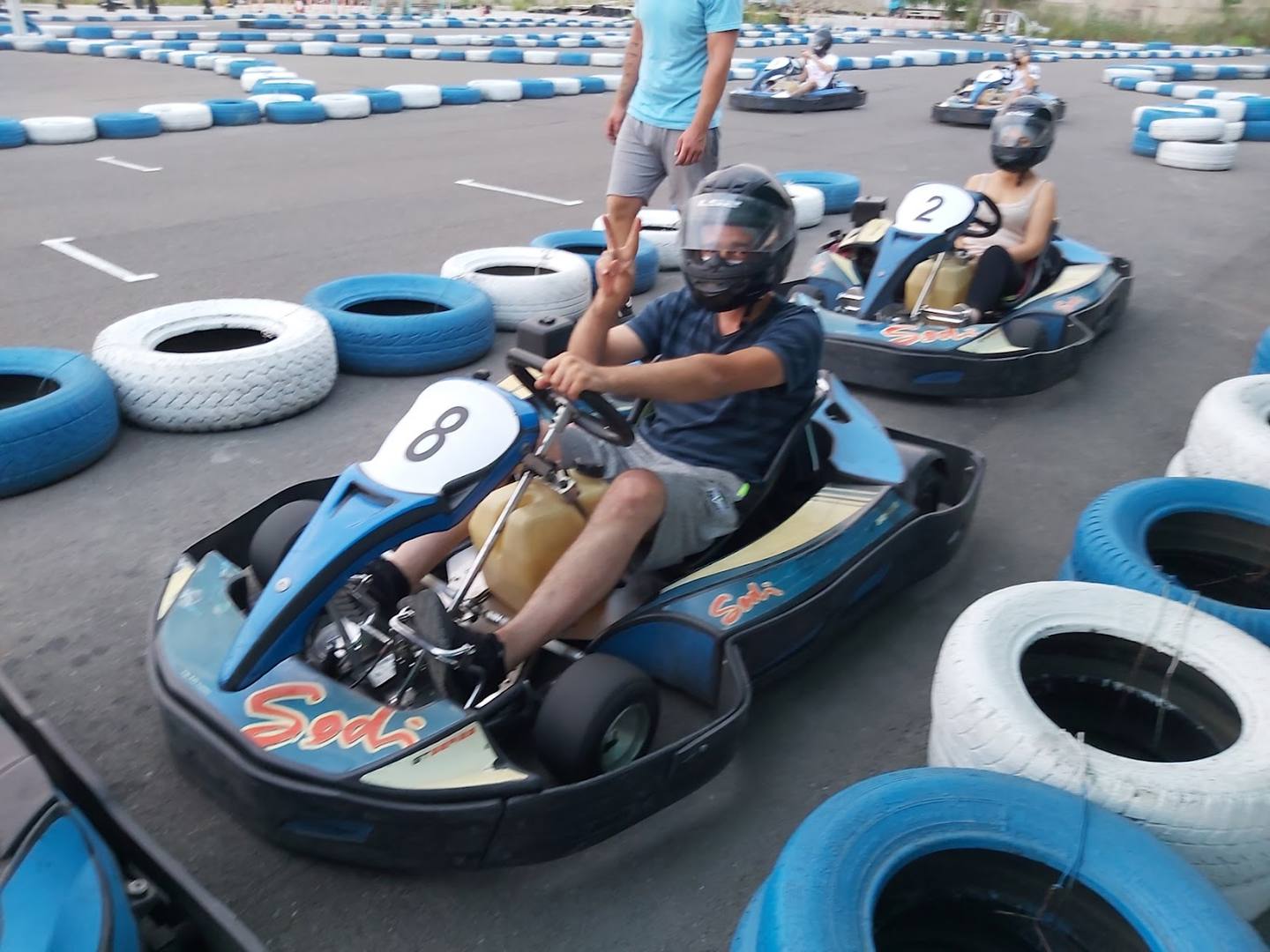 Go-kart racing on indoor track with blue and white barriers