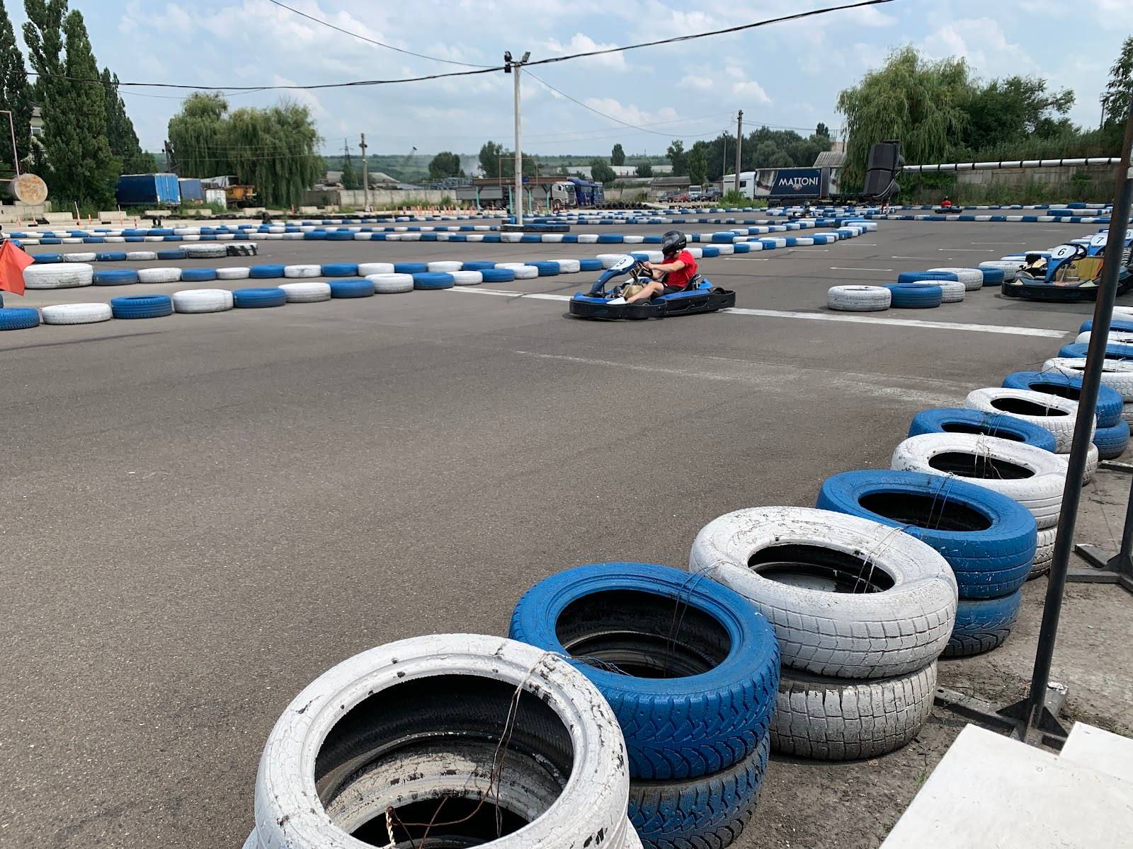 Go-kart track with blue and white painted tires and karts racing in the distance