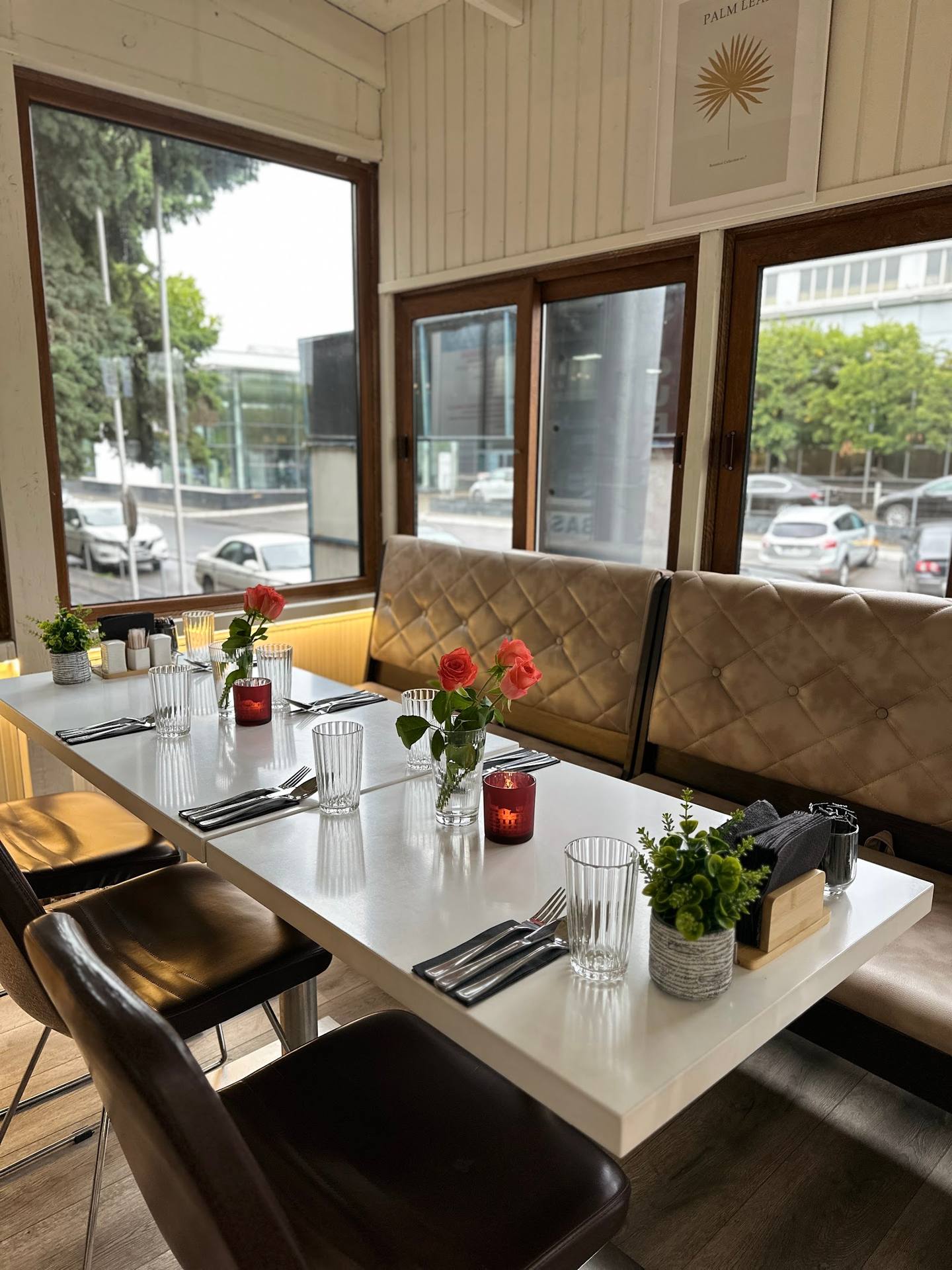 Modern dining booth with street-view windows and fresh table setting in contemporary restaurant