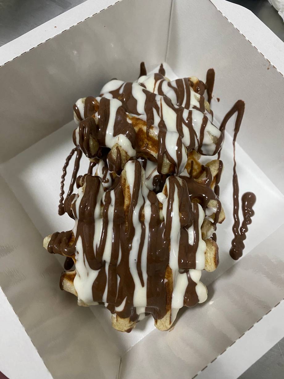 Dessert with chocolate drizzle and whipped cream on white paper