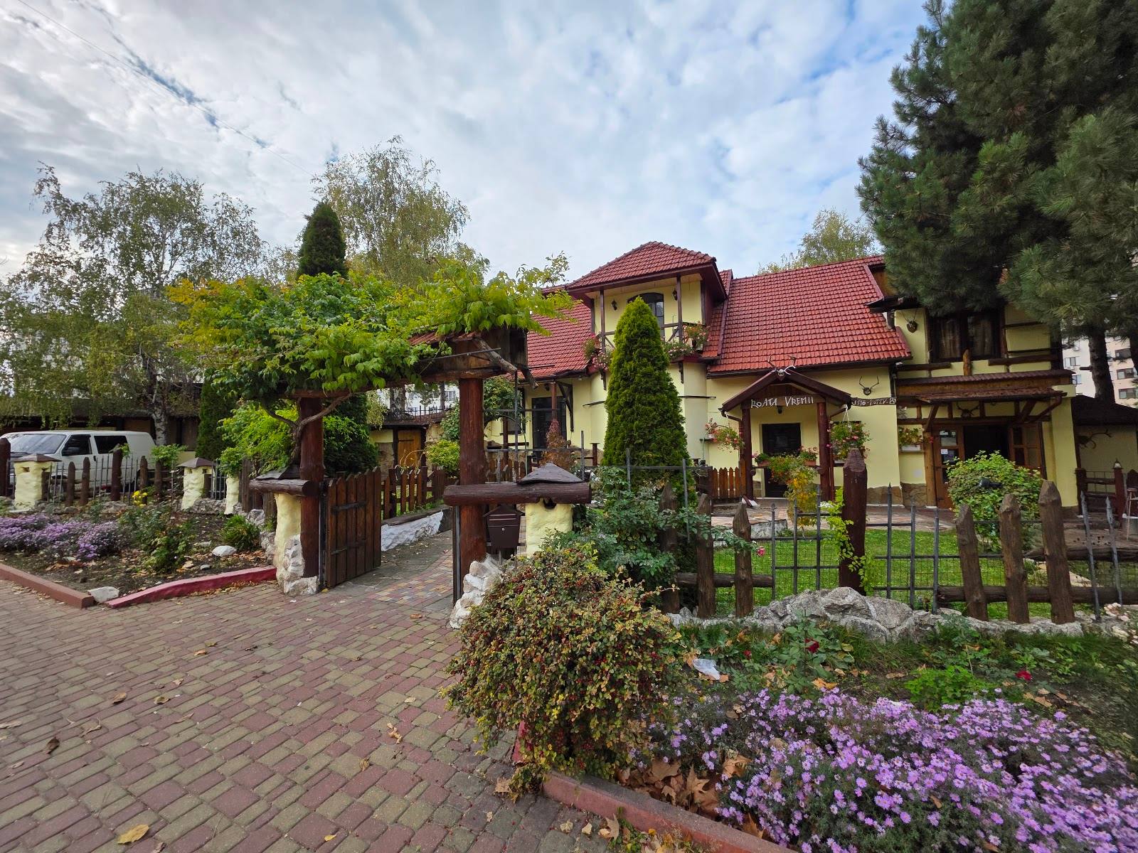 Stone terrace and Mediterranean-style building with red tile roof, ivy-covered walls, and flowering gardens