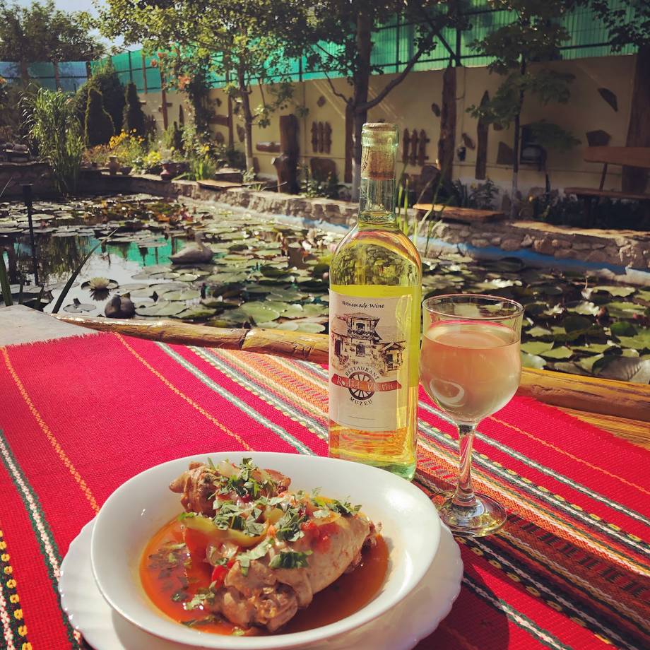 Wine and traditional dish served on red tablecloth in open-air courtyard