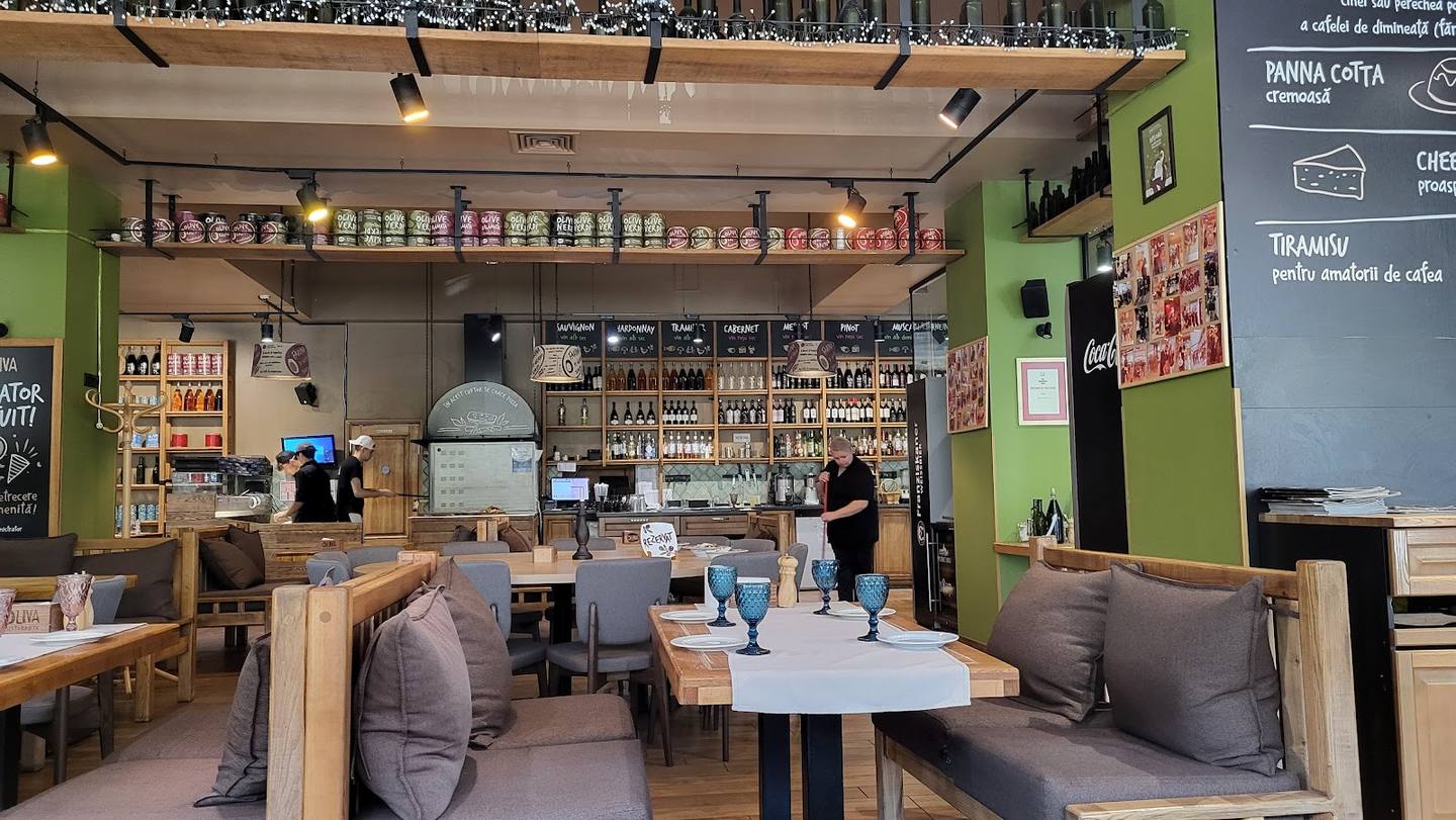 Modern cafe interior with green walls, wooden seating, and counter display case