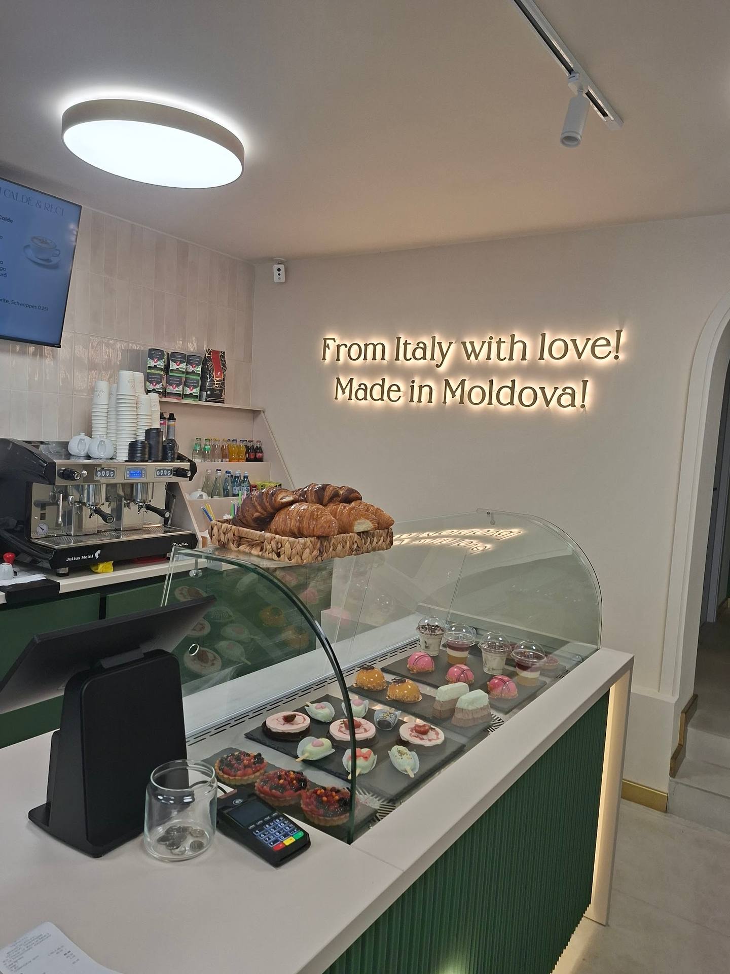 Italian bakery/café counter with pastries, pastry case, and espresso machine, bright modern interior