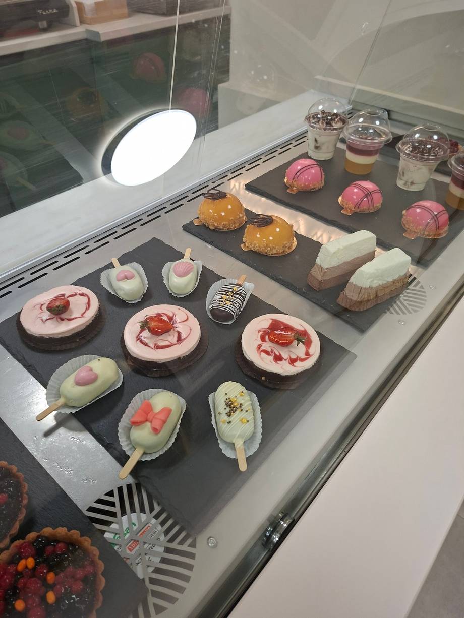 Artisanal pastry and dessert display case with macarons, cakes, and decorated bites