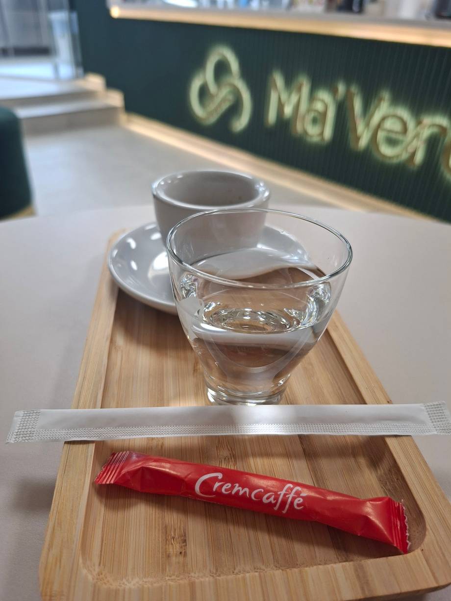Coffee service with water glass and Cremcaffe sugar packet at Mai Vert café
